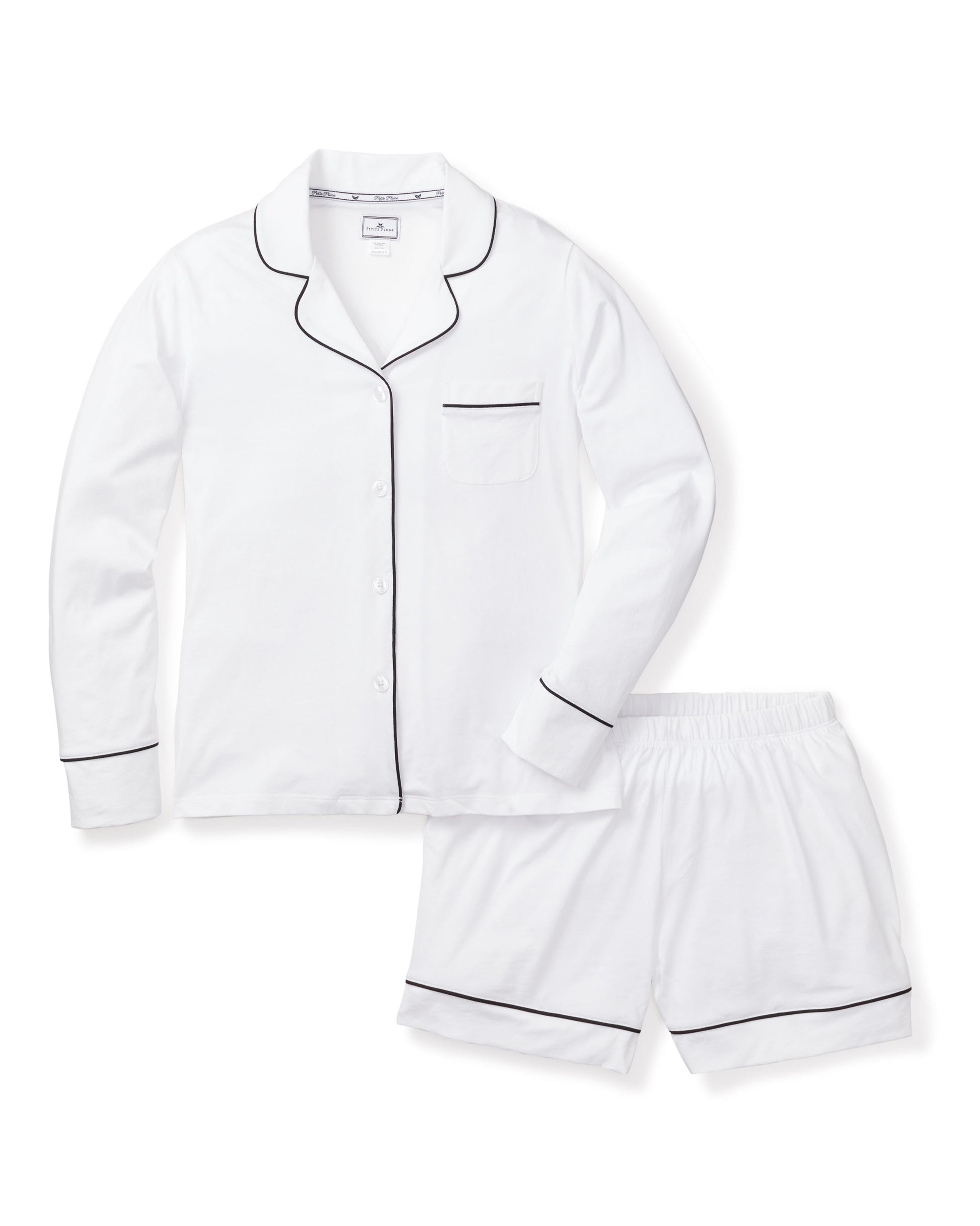 The Womens Pima Long Sleeve Short Set by Petite Plume is a luxurious pajama ensemble in white with black piping, made from soft Peruvian Pima cotton. It includes a button-up top with a pocket and shorts with an elastic waistband, all presented against a plain white background.