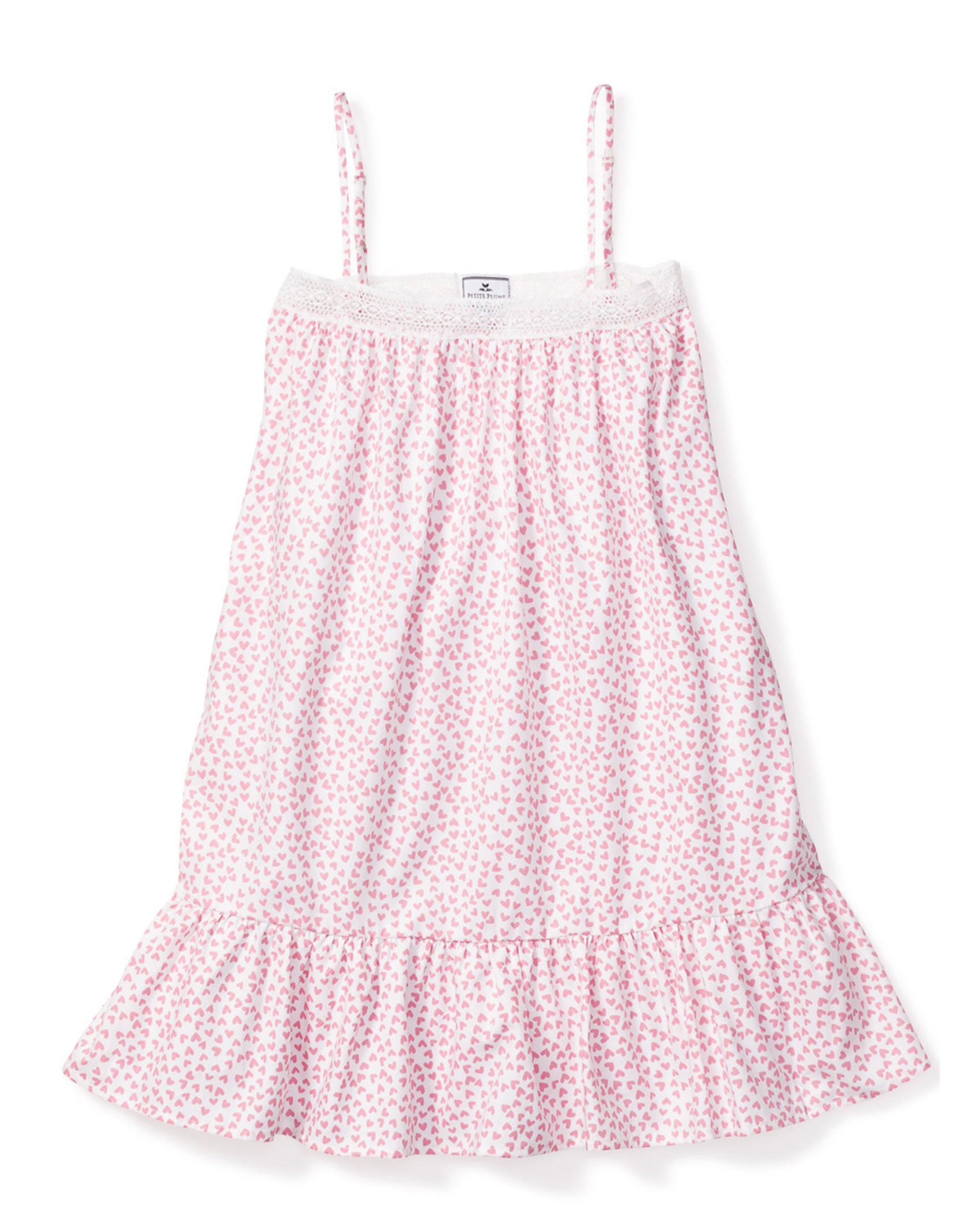 The Girls Twill Lily Nightgown in Sweethearts by Petite Plume is a luxurious sleeveless, knee-length sleepwear piece. It features thin straps, a pink heart pattern on a white background, and is crafted from yarn-dyed cotton with a textured upper section and ruffled bottom hem.