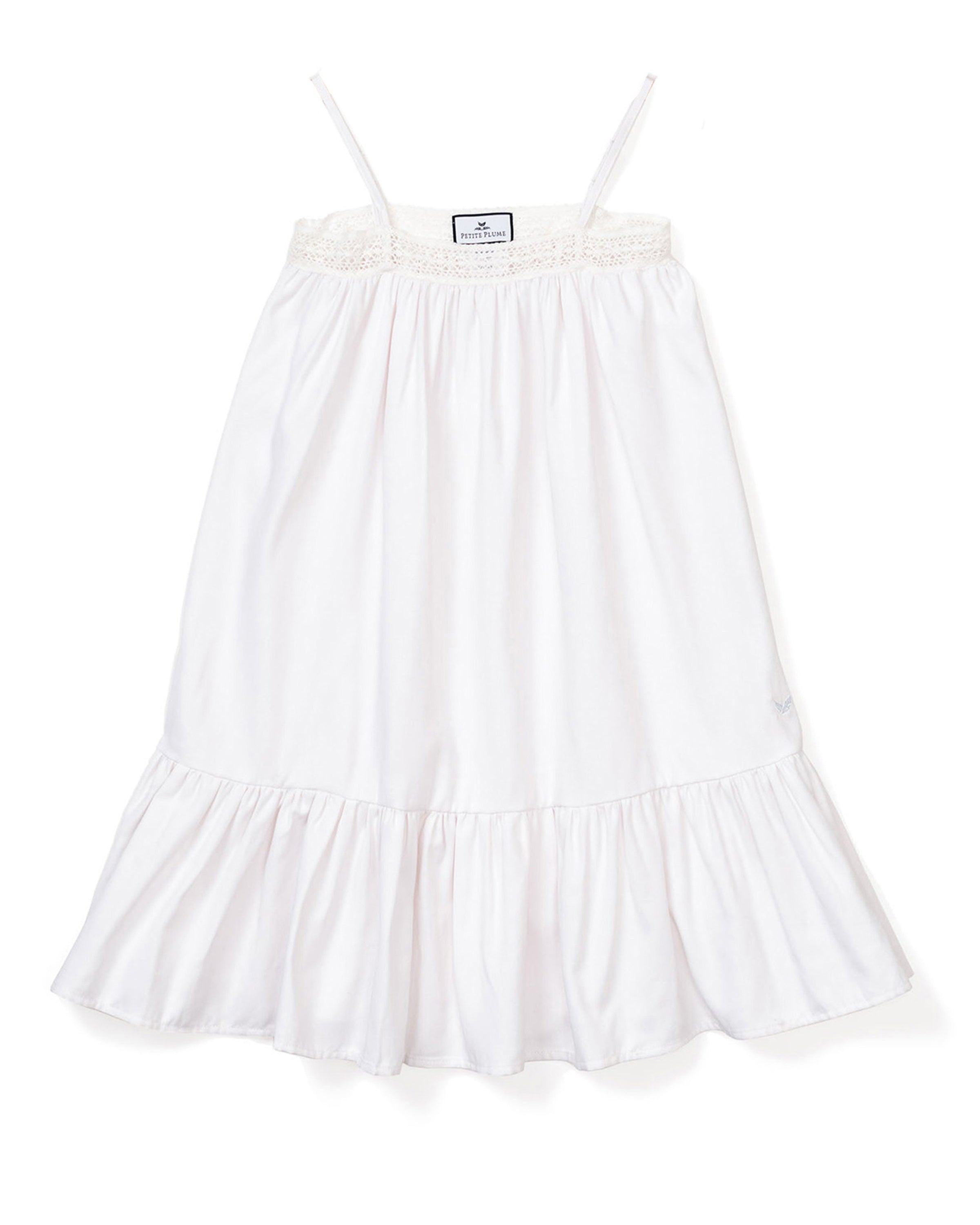 The Girls Twill Lily Nightgown in White by Petite Plume is sleeveless with thin straps, a smocked bodice, and a ruffled hem. Made from yarn-dyed cotton, its light and flowing, perfect for warm weather.