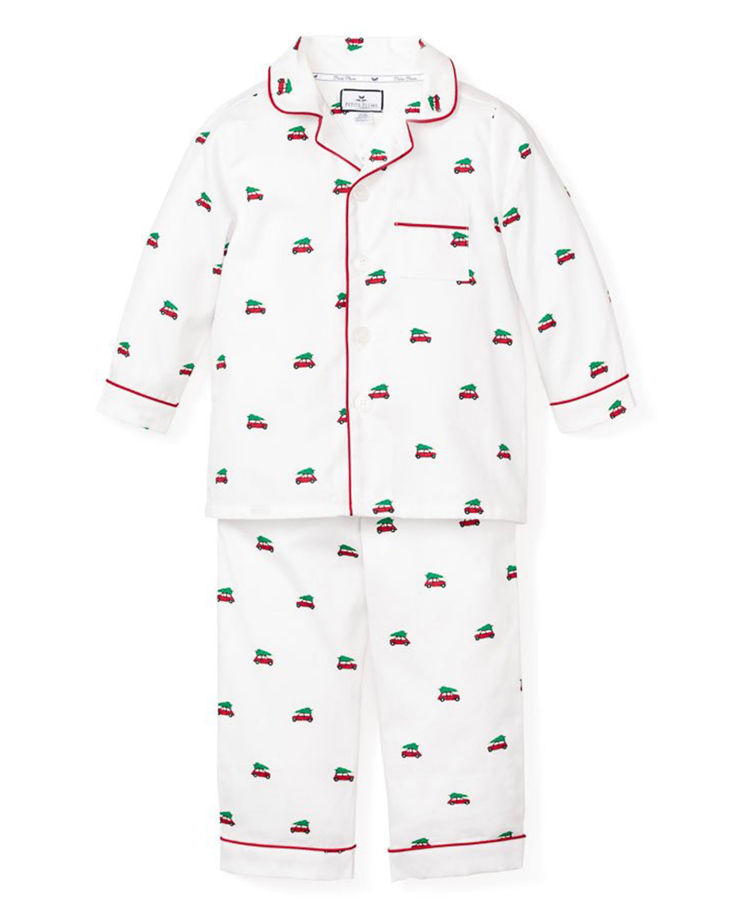 The Kids Twill Pajama Set in Holiday Journey by Petite Plume features a white pajama set with red piping, including a long-sleeve button-up shirt and matching pants, adorned with colorful car designs for a cozy holiday.